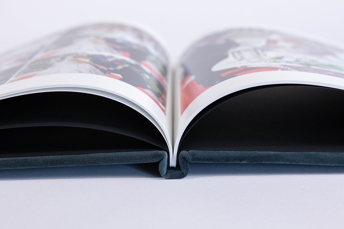 Deep Sea Blue velvet coffee table book lying open, showing its printed wedding photo pages