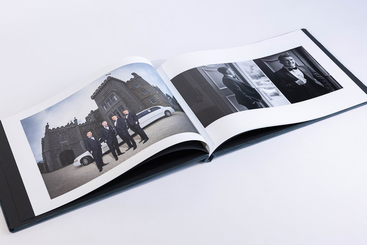 Deep Sea Blue velvet coffee table book open at a wedding photo spread of the groom and groomsmen