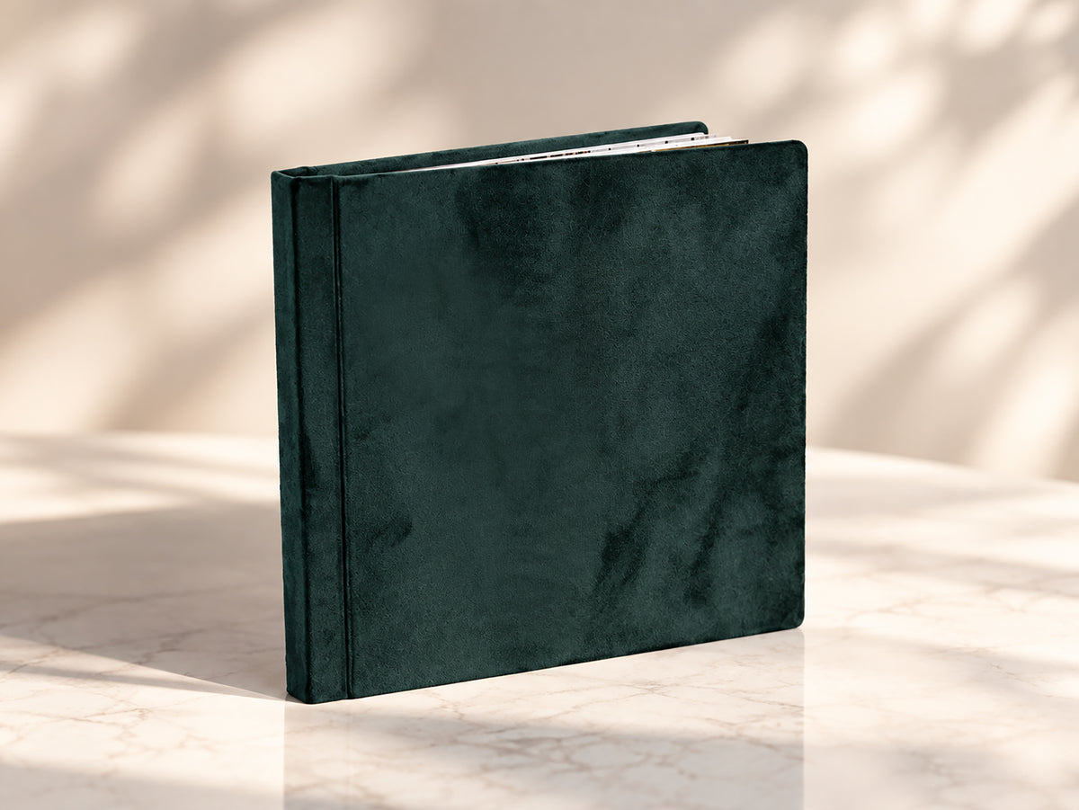 Emerald green velvet wedding album standing on a marble table