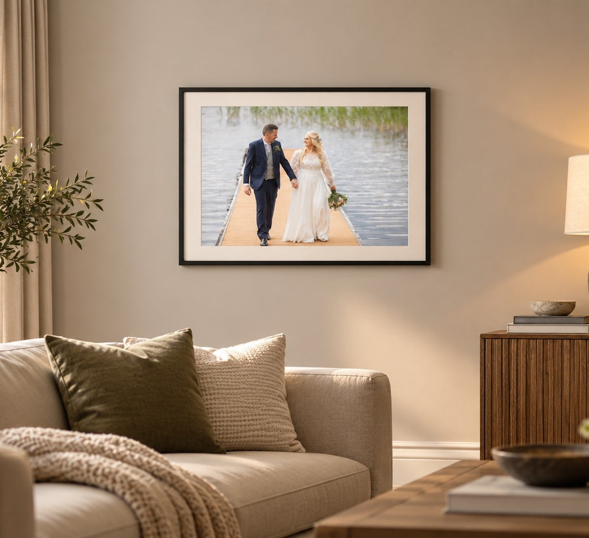 Framed wedding photo print in a black frame with a white mount, hanging in a living room