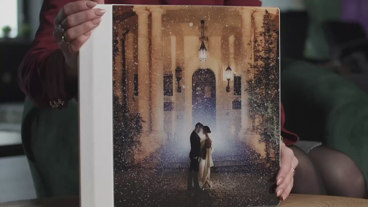 Acrylic photo cover wedding album held in hand, with a full-page acrylic front showing the couple's wedding photo and a Frothy White vegan leatherette spine